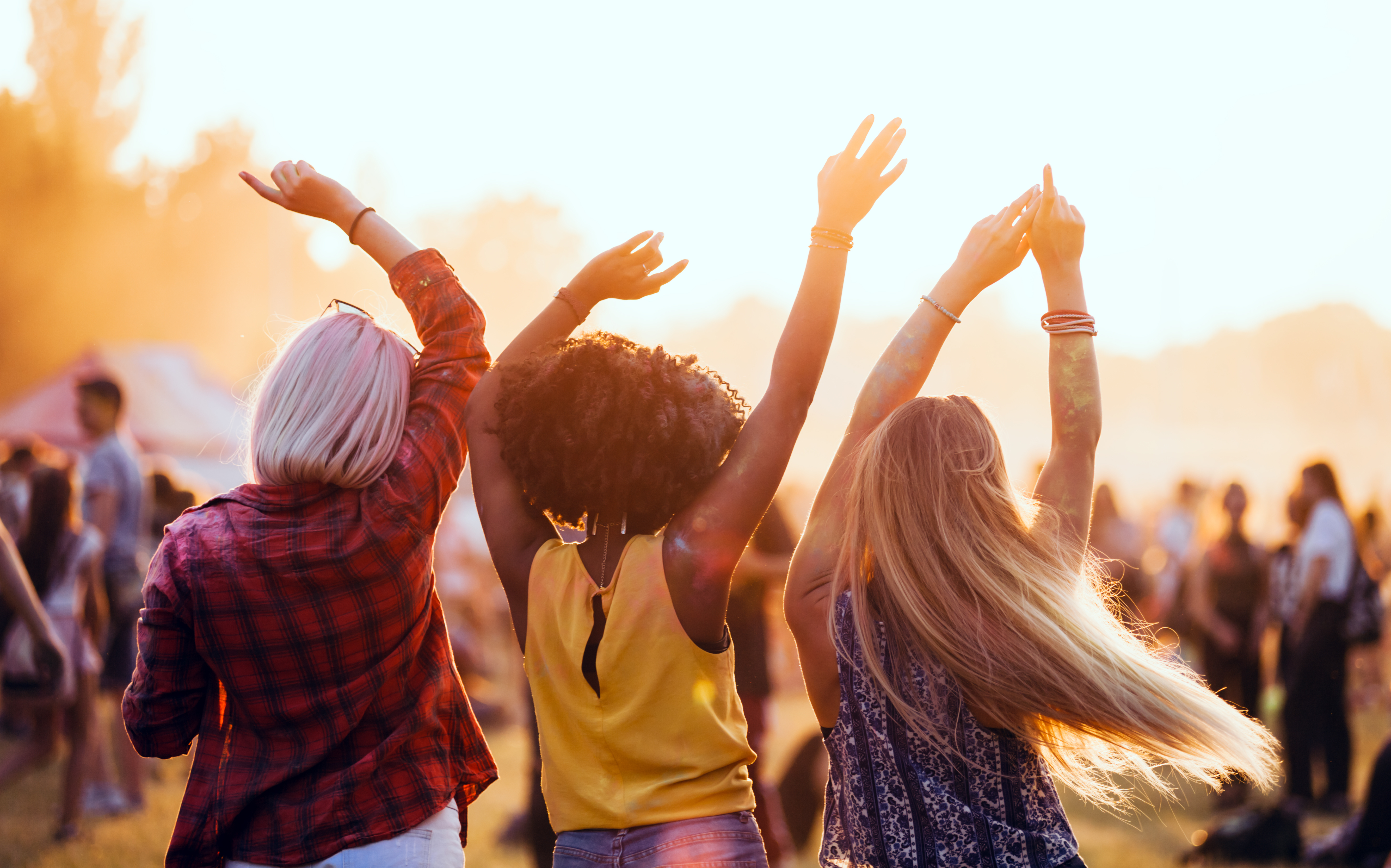 Friends dancing joyfully together at an outdoor festival at sunset
